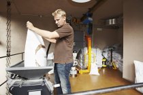 Чоловік просіює зерна на вагових вагах у пивоварні — стокове фото