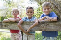 Портрет троих детей, опирающихся на садовый забор — стоковое фото