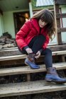 Giovane donna seduta sul gradino, allacciatura lacci stivali — Foto stock
