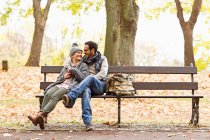 Улыбающаяся пара сидит на скамейке в парке — стоковое фото