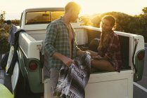 Surfing couple in back of pickup truck at sunset at Newport Beach, California, USA — Stock Photo