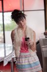 Молода жінка тримає мобільний телефон в їдальні, портрет — стокове фото