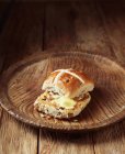 Масляна хрестоподібна булочка на старовинній дерев'яній тарілці — стокове фото