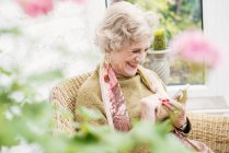 Старша жінка за допомогою мобільного телефону в саду — стокове фото
