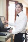 Portrait of waiter using touch screen on cash register in restaurant — Stock Photo
