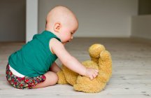 Menina bebê brincando com ursinho de pelúcia no chão — Fotografia de Stock