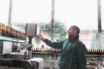 Trabalhador da cervejaria operando máquina de engarrafamento — Fotografia de Stock