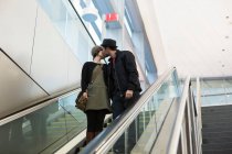 Couple kissing on escalator outdoors — Stock Photo