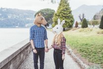 Couple portant des masques de cheval et de lapin tenant la main, Lac de Côme, Italie — Photo de stock