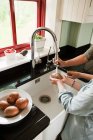 Мати і син миють картоплю в кухонній мисці — стокове фото