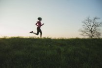 Young female runner silhouetted on hill — Stock Photo