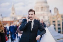 Бізнесмен розмовляє на смартфоні, коли спирається на міст Мілленіум (Лондон, Юк). — стокове фото
