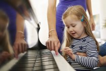 Parents teaching daughter to play piano — Stock Photo