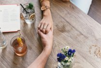 Cropped image of Romantic young couple holding hands over restaurant table — Stock Photo