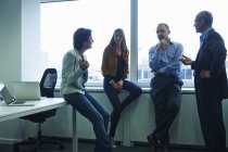 Чоловіки і жінки бізнесмени спілкуються в офісі — стокове фото