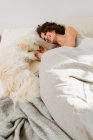 Жінка розслабляється в ліжку з собакою — стокове фото
