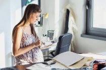 Pregnant woman in office using digital tablet — Stock Photo