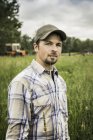 Junger Mann auf Bauernhof kaut Gras und blickt in Kamera — Stockfoto