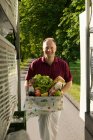 Smiling deliveryman with a box of groceries — Stock Photo