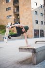Young male skateboarder doing balance skateboard trick on urban concourse seat — Stock Photo