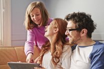 Mid adult parents and daughter on sofa looking at digital tablet — Stock Photo