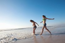 Dos chicas corriendo en la playa - foto de stock