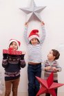 Children holding up Christmas decorations — Stock Photo