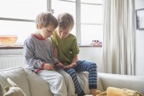 Two little brothers using smartphone at home, London, UK — Stock Photo