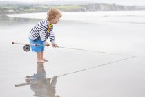 Хлопчик стоїть на пляжі з вудкою — стокове фото
