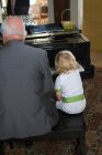 Молодий хлопчик грає на піаніно з дідом — стокове фото