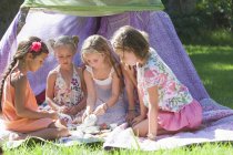 Cinque ragazze che giocano con il tè giocattolo in giardino — Foto stock