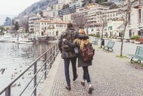 Vue arrière d'un jeune couple se promenant le long du lac de Côme, Italie — Photo de stock