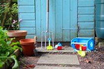 Gardening tools, pots and toys outside shed — Stock Photo