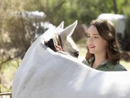 Adolescente chica aseo caballo gris - foto de stock
