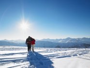 Vue arrière du couple marchant dans la neige au sommet de la montagne — Photo de stock