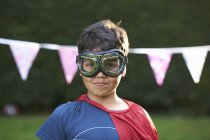 Portrait of boy wearing goggles and cape, looking at camera — Stock Photo