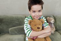 Портрет мальчика на диване, обнимающего Тедди — стоковое фото