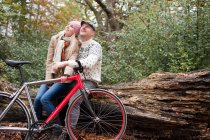 Пара сидить на колоді з велосипедом — стокове фото