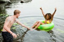 Пара играет на надувном кольце на озере — стоковое фото