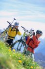 Гірські велосипедисти несуть свої велосипеди — стокове фото