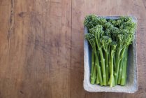 Tub of fresh broccoli on table, top view — Stock Photo