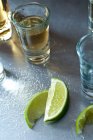 Tequila shots with lime slices and salt on table — Stock Photo