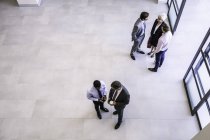 High angle view of businesswoman and businessmen having discussions in office atrium — Stock Photo