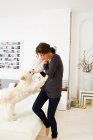 Femme jouant avec chien dans le salon — Photo de stock