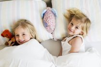 Ritratto di due sorelline sdraiate fianco a fianco a letto — Foto stock