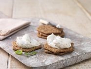 Garlic and herb soft cheese on hexagon crackers on whitewashed cutting board — Stock Photo
