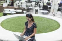 Жінка використовує ноутбук біля відкритого кафе — стокове фото