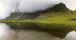 Nuvens baixas sobre montanhas refletindo na água do lago — Fotografia de Stock