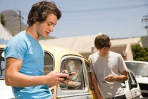 Teenage boys listening to mp3 player and playing video game — Stock Photo