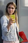 Mulher jovem, ao ar livre, usando fones de ouvido, tirando selfie com smartphone — Fotografia de Stock